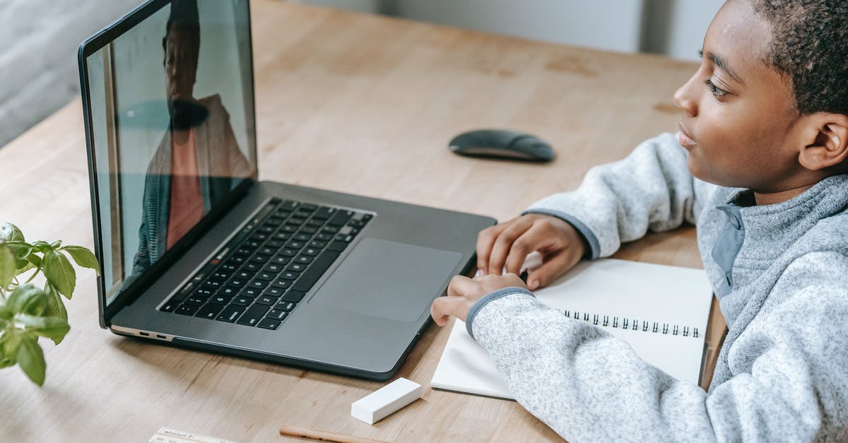 Which class or classes are the most self-sufficient? - From above side view of crop African American schoolchild watching netbook with speaking female teacher during distance learning at table