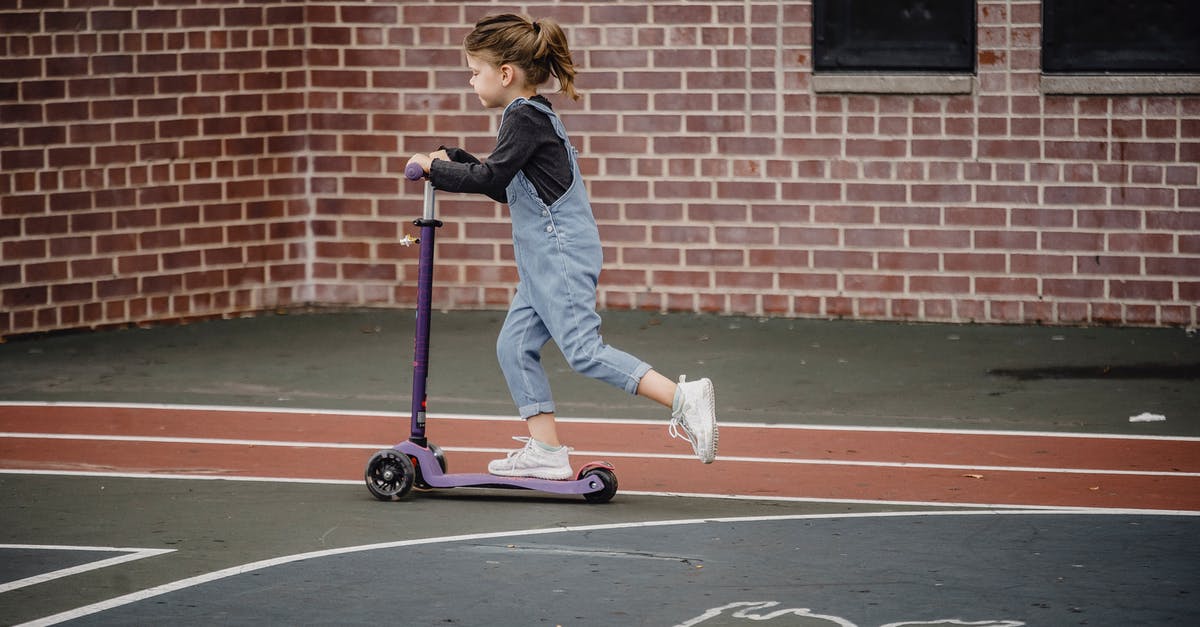 Which heroes move the fastest along the ground? - Side view of excited preschool girl in casual outfit riding scooter on asphalt sports ground Which heroes move the fastest along the ground? - Side view of excited preschool girl in casual outfit riding scooter on asphalt sports ground