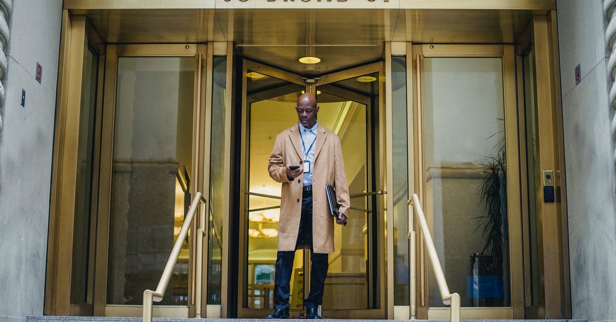 Which outfit should I use for vault entrance guards? - Black man receiving message on smartphone on stairs of building