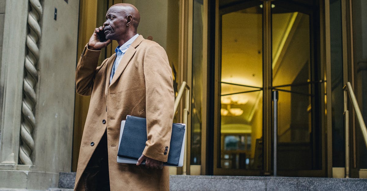 Which outfit should I use for vault entrance guards? - African American male in formal outfit talking on mobile phone near entrance of modern building