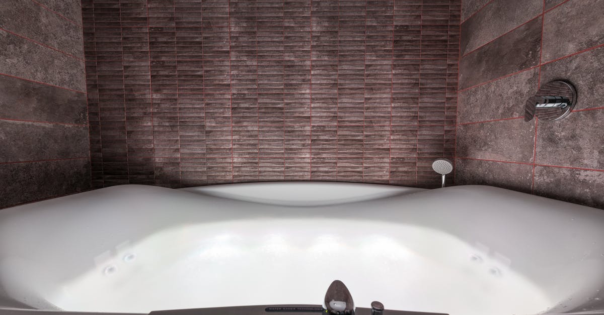 Which parts panel contains control surfaces? - Modern white ceramic tub with illumination and contemporary control panel with buttons and levers placed in stylish bathroom among walls
