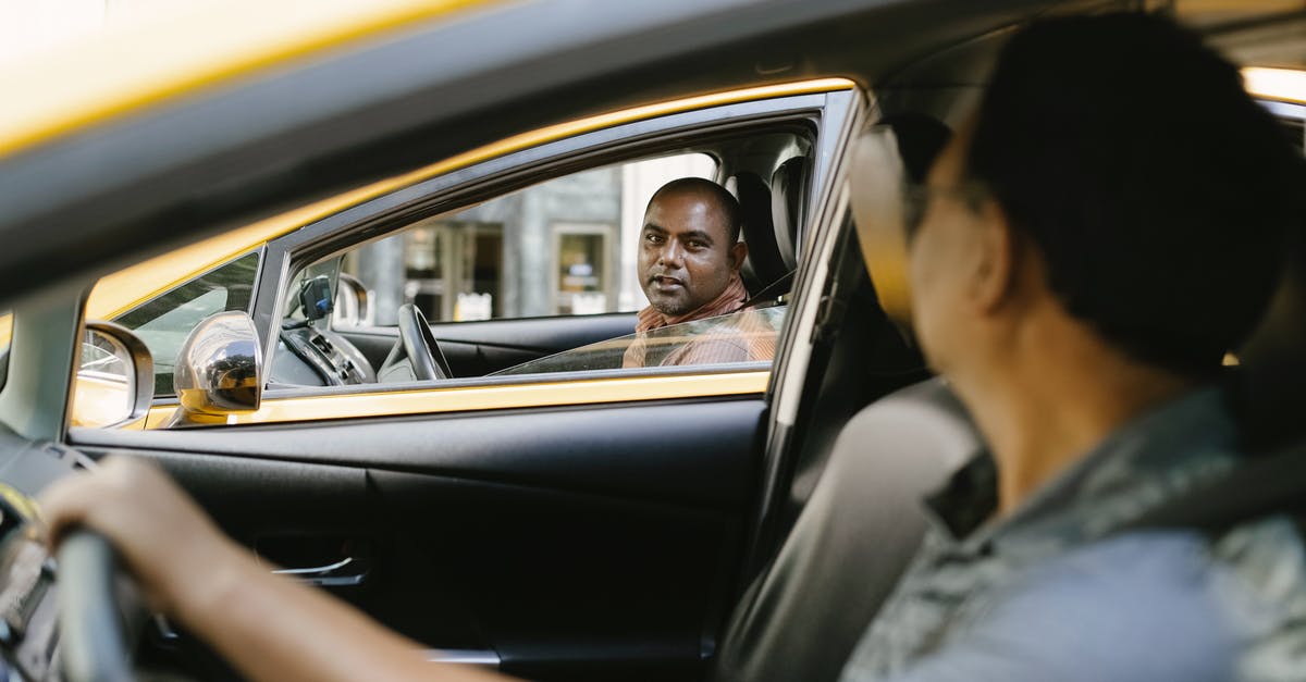 Which PS2 games required a Hard Drive to work? - Side view of adult ethnic male cab driver interacting with anonymous colleague driving auto while looking at each other in city