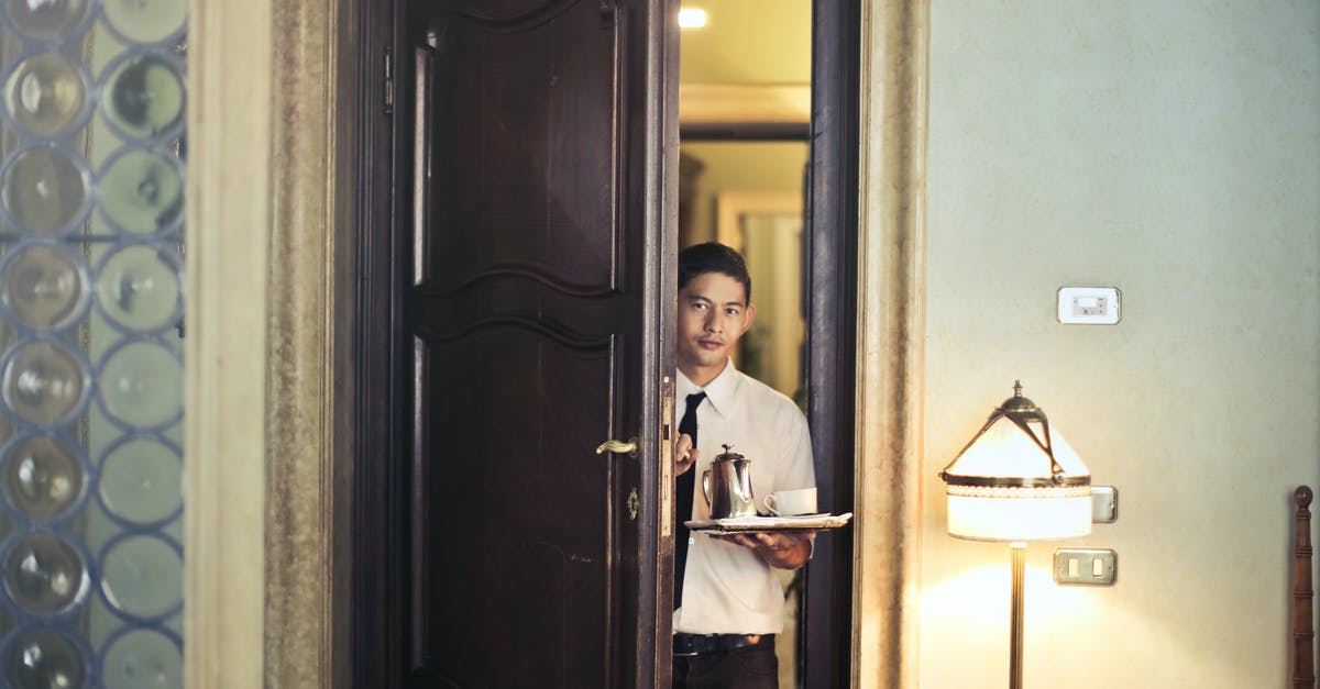 Which room gets entered in the contest? - Young ethnic male room service waiter carrying tray with coffee pot while entering hotel room with stylish vintage interior