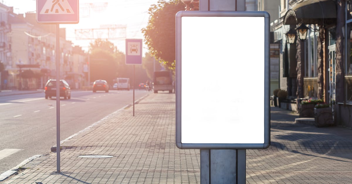 Who are these ghostly figures in the Route B ending? - Blank advertisement on tiled walkway with road signs and building in town on sunny day