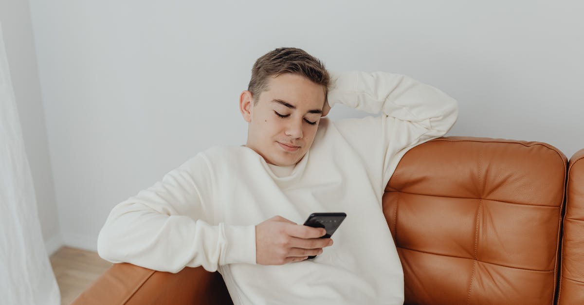 Who has the biggest head? - Teenage Boy Sitting on the Sofa and Using a Smart Phone Who has the biggest head? - Teenage Boy Sitting on the Sofa and Using a Smart Phone