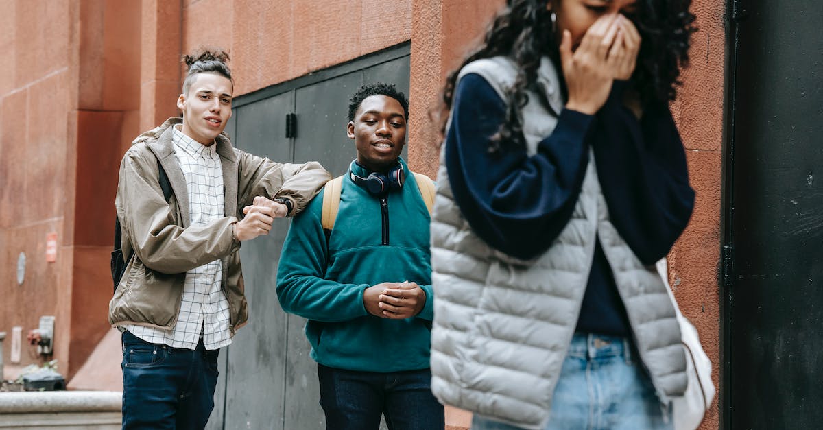 Whoa, A Bad Relationship - Low angle of annoyed young ethnic lady covering mouth and crying after being abused by rebellious multiracial male groupmates Whoa, A Bad Relationship - Low angle of annoyed young ethnic lady covering mouth and crying after being abused by rebellious multiracial male groupmates