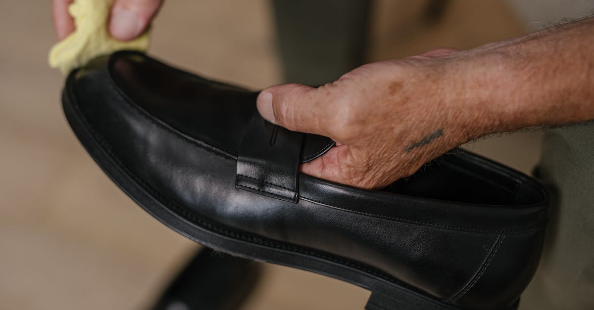 Whose Brahmin is this? I'm not cleaning up after it - Person Holding Black Leather Shoe
