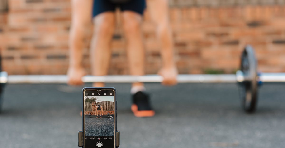 Why am I much faster than the record, but not the record holder? - Unrecognizable bodybuilder lifting barbell behind smartphone recording video in town Why am I much faster than the record, but not the record holder? - Unrecognizable bodybuilder lifting barbell behind smartphone recording video in town