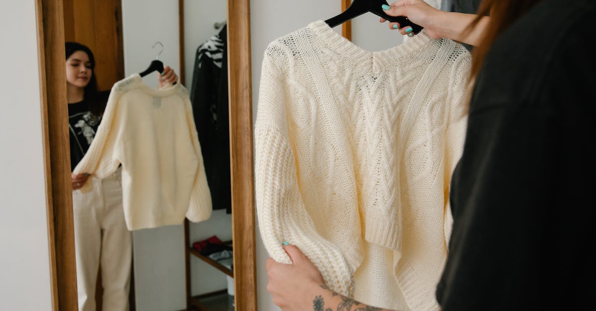 Why am I trying to kill people with a defibrilator? - Woman Holding White Knitted Sweater on Hanger In Front of a Mirror 
