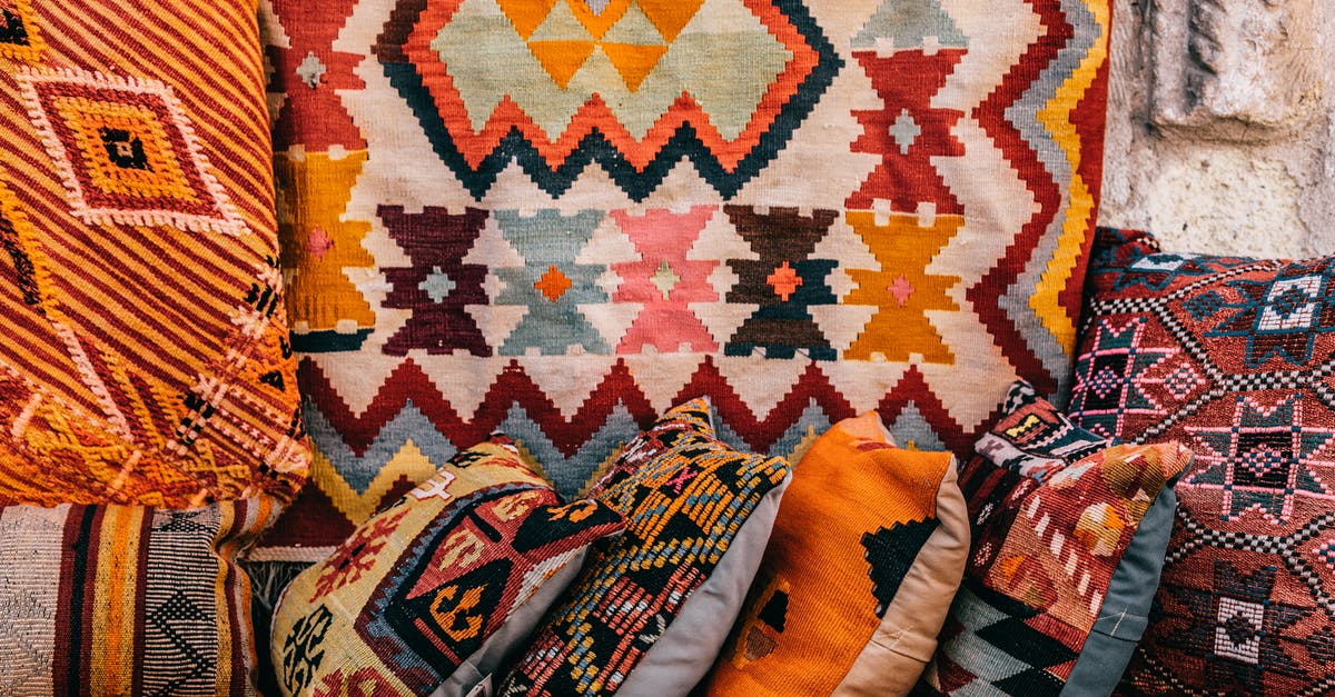 Why am I unable to purchase a tile outside of my current cultural area? - Colorful pillows with patterns placed on couch near abundance of ornamental oriental carpets on bazaar in old city on street