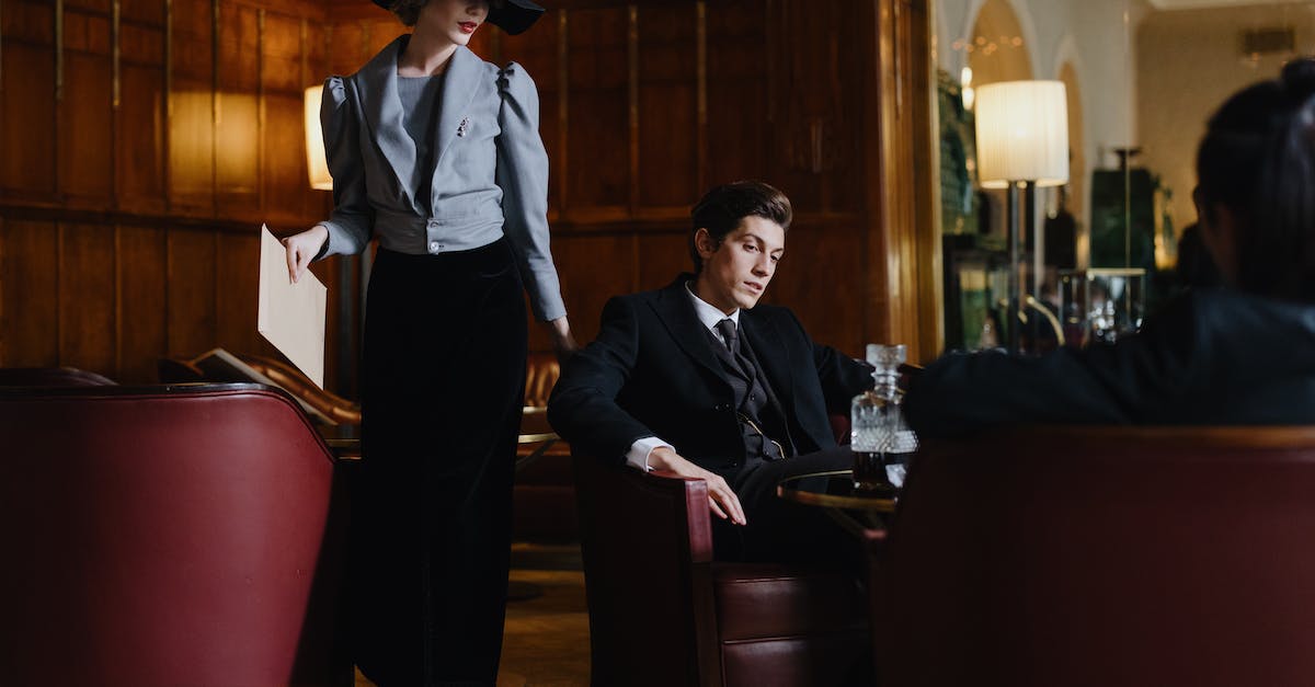 Why are my clan members ineligible for wars? [duplicate] - A Woman in Gray Blazer and Black Skirt Standing Near the Man in Black Suit Sitting on the Chair