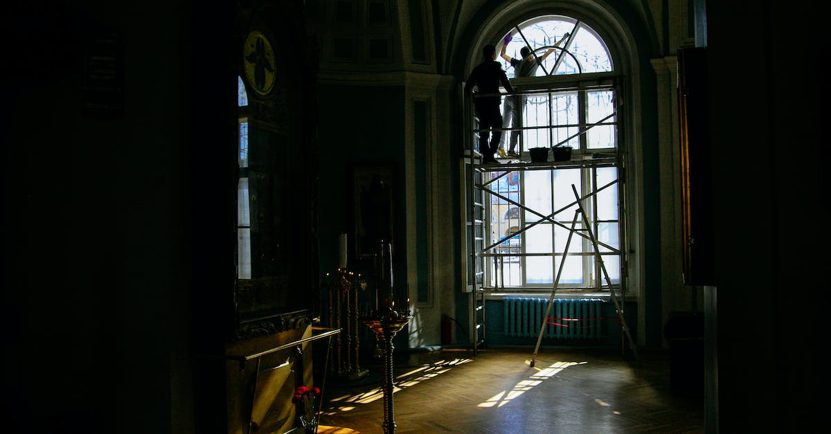Why arent all of my workmen working? - Back view of anonymous workmen on scaffold near arched window during restoration process in aged house Why arent all of my workmen working? - Back view of anonymous workmen on scaffold near arched window during restoration process in aged house
