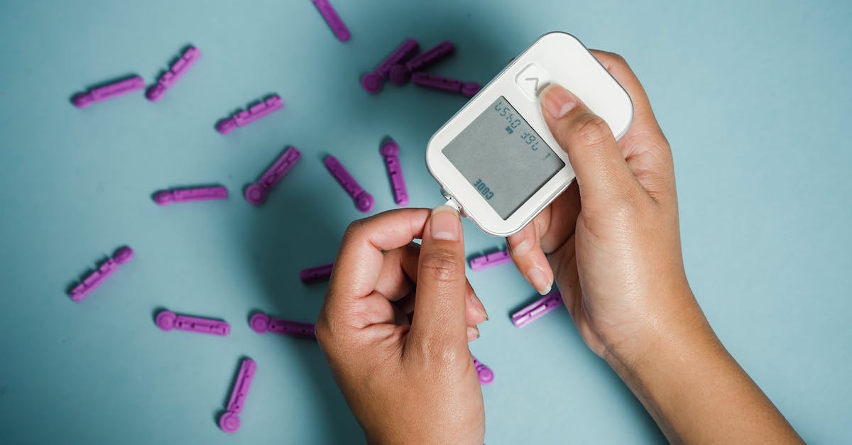 Why button check? - Top view of crop anonymous female diabetic measuring blood sugar with glucometer over scattered lancets Why button check? - Top view of crop anonymous female diabetic measuring blood sugar with glucometer over scattered lancets