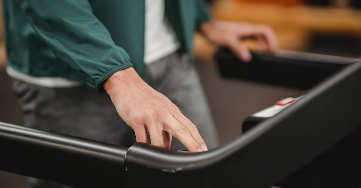 Why button check? - Crop anonymous male in activewear checking speed and time of treadmill on blurred background Why button check? - Crop anonymous male in activewear checking speed and time of treadmill on blurred background