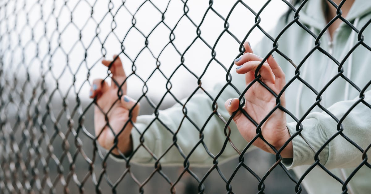 Why can't I destroy this energy barrier with my melee attack? - Crop unrecognizable woman touching net fence on street