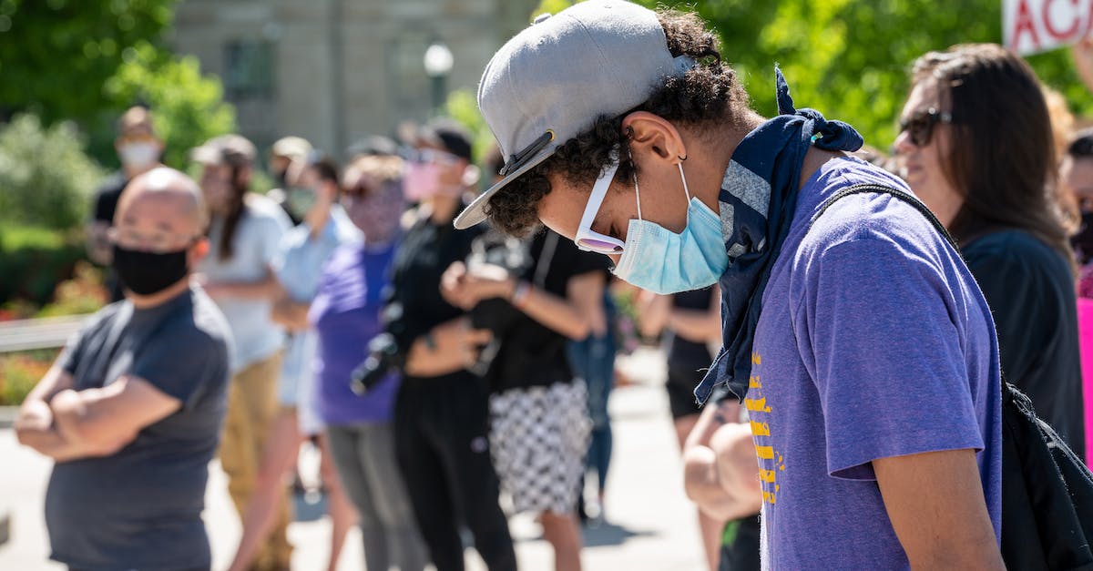 Why can't I fight Omega Mark XII? - Side view of guy in casual clothes and cap and protective mask standing against crowd at sunny day
