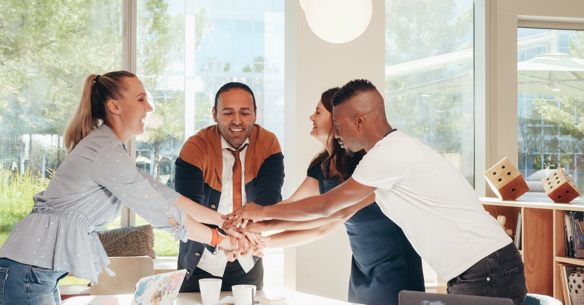 Why can't I join a friend's world on Minecraft PE? - Content multiethnic colleagues joining hands above table with laptops in modern office on sunny day