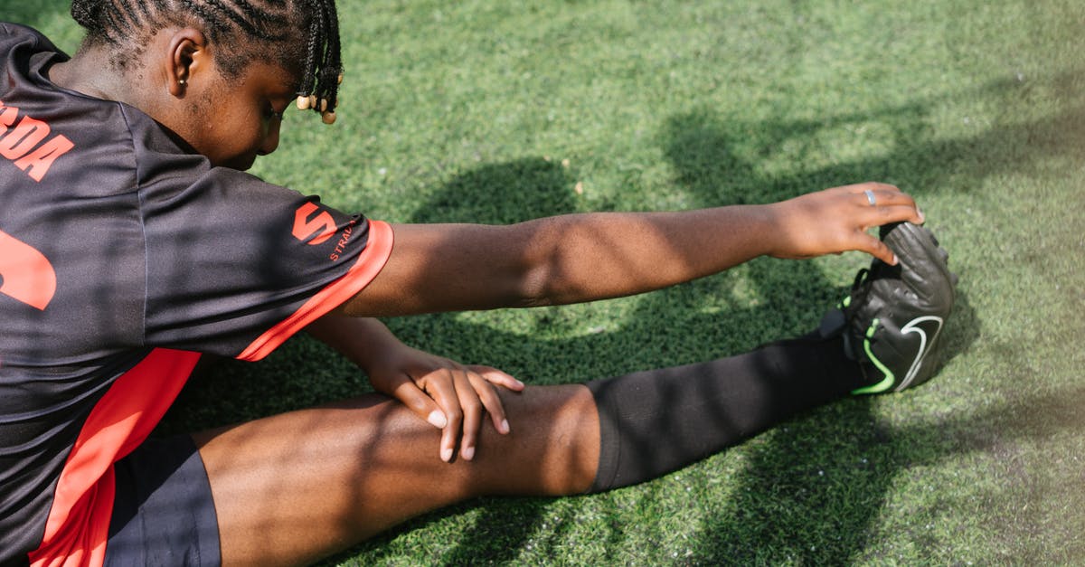 Why did I encounter cards from a higher arena from my opponent? - From above of black female soccer player sitting on green grass and stretching before coming on field