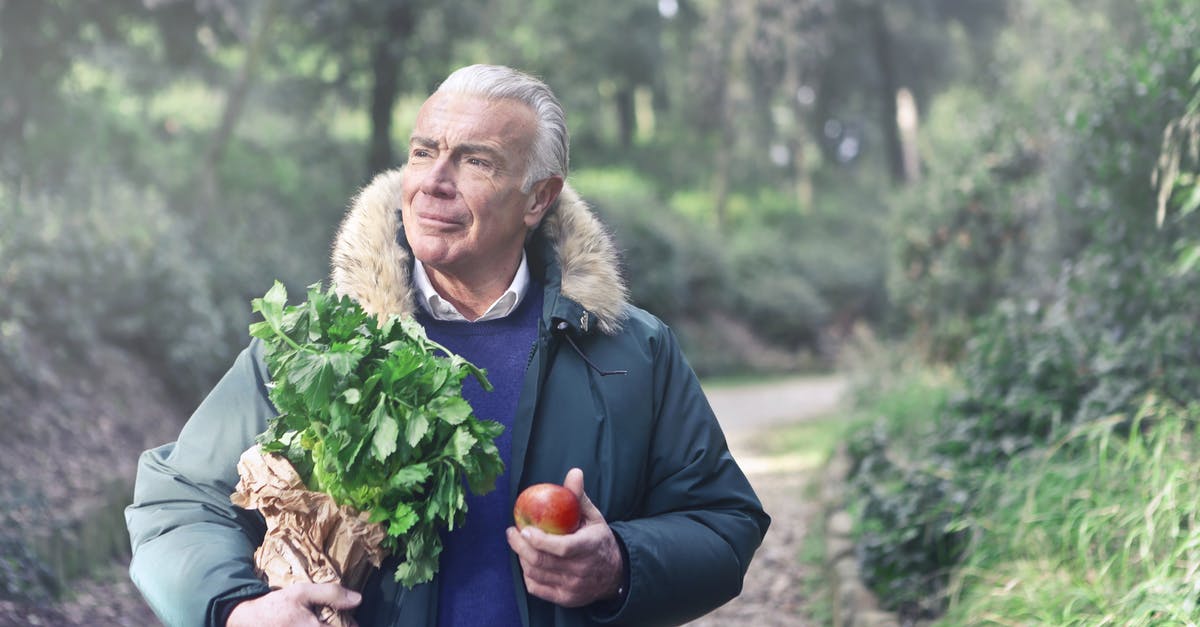 Why did some of my fruit trees not grow to the next stage? - Man in Blue Jacket Holding Green Plants and Red Apple