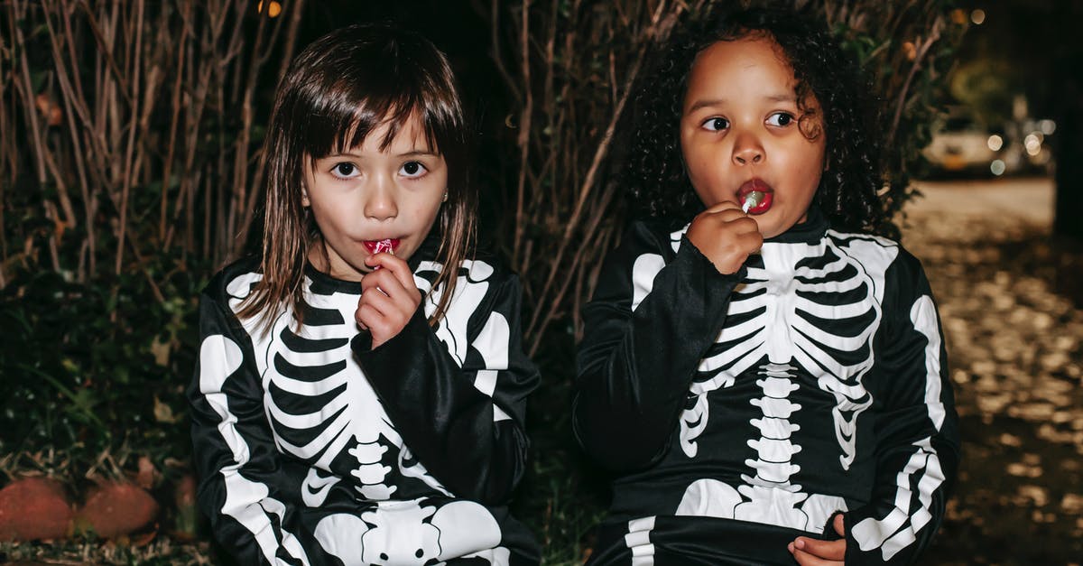 Why do I get tons of medals in custom games against AI? - Positive little multiracial girls wearing traditional skeleton costumes and enjoying sweet stick candies while sitting on brick border in autumn park after playing Trick or Treat game