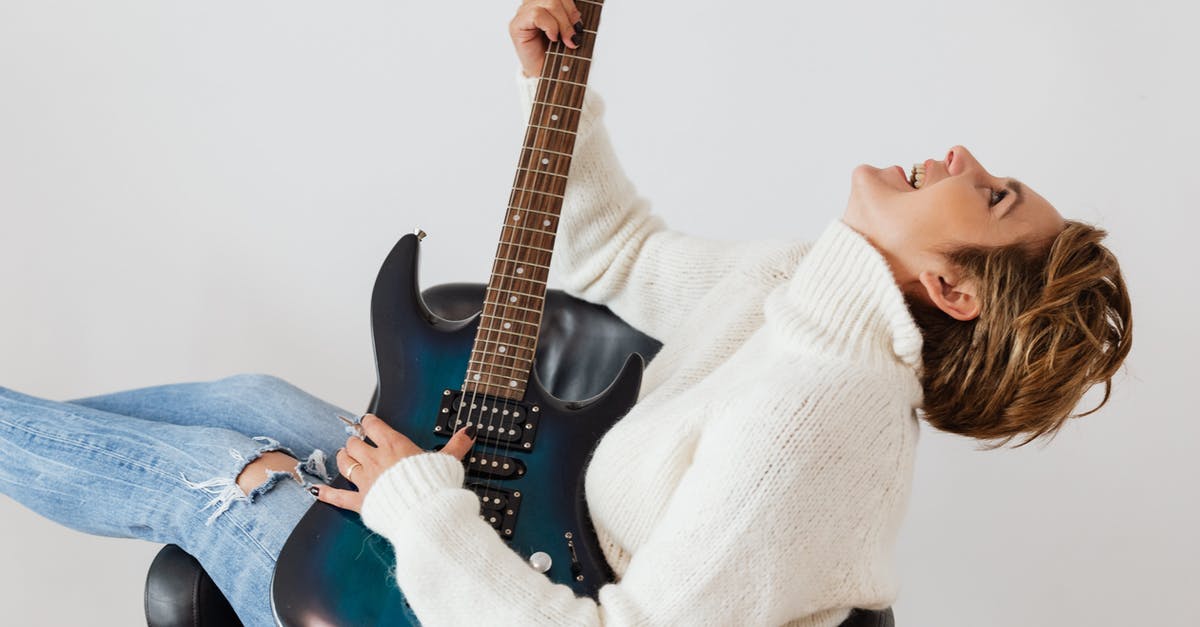 Why do I have staticy sound? - Side view of cheerful short haired female in casual clothes laughing while playing electric guitar in comfortable armchair against white background Why do I have staticy sound? - Side view of cheerful short haired female in casual clothes laughing while playing electric guitar in comfortable armchair against white background