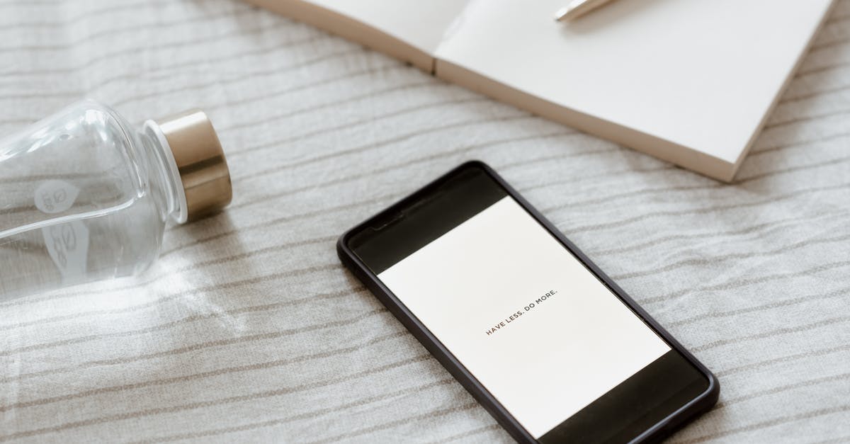 Why do I have staticy sound? - From above of cellphone with Have Less Do More inscription on screen near empty notebook and bottle of water Why do I have staticy sound? - From above of cellphone with Have Less Do More inscription on screen near empty notebook and bottle of water