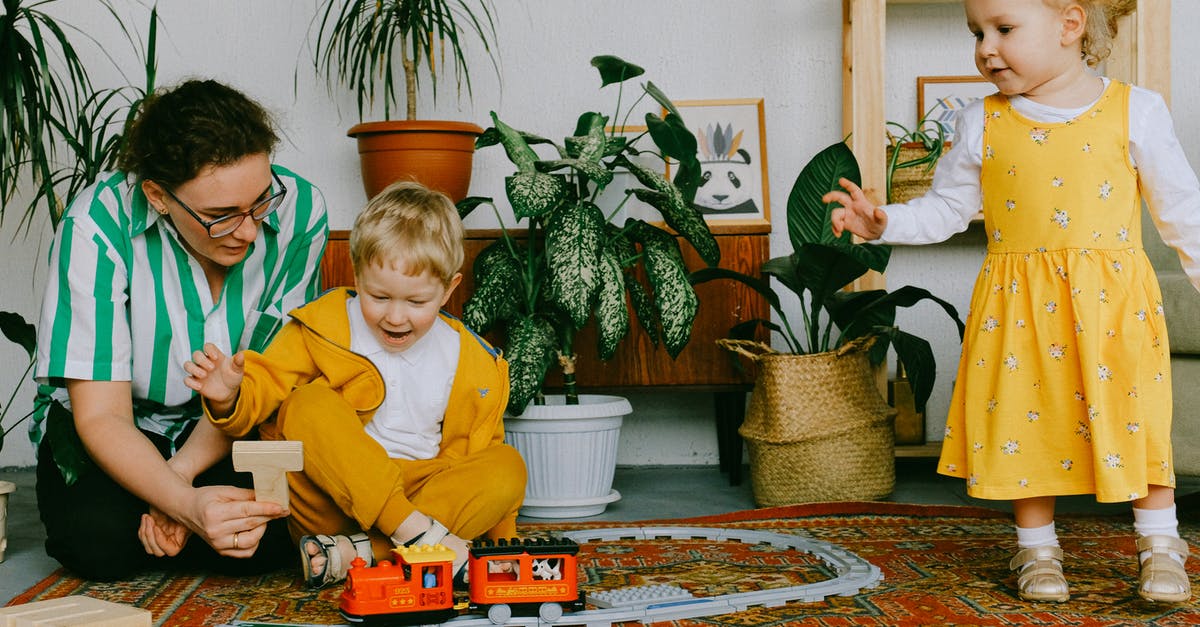 Why do I have to re-download games? - Mom and adorable little brother and sister in casual wear gathering in cozy living room during weekend and having fun together while playing with plastic railway