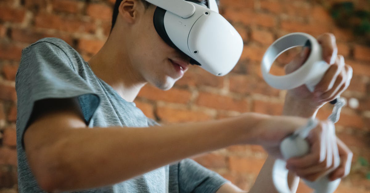 Why do I sometimes experience a delay despite a very low ping? - Crop young male in casual clothes using goggles of virtual reality and controllers while standing near brick wall