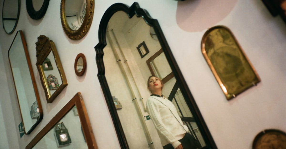 Why do my Planetary Portals sometimes look different? - Contemplative young female in casual wear standing on stairs and reflecting in one of many framed mirrors hanging on wall