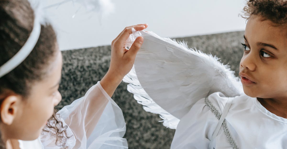 Why do some of my 4* heroes have a lower feather cost to unlock potential? - Crop anonymous African American girl playing with wing of angel costume of little cute brother looking away