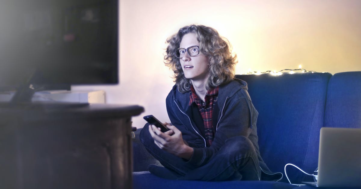 Why does connecting a laptop to a TV via HDMI cause a framerate drop? - Concentrated male with long hair sitting on comfortable sofa at home and messaging on social media via cellphone while watching movie on TV with opened mouth