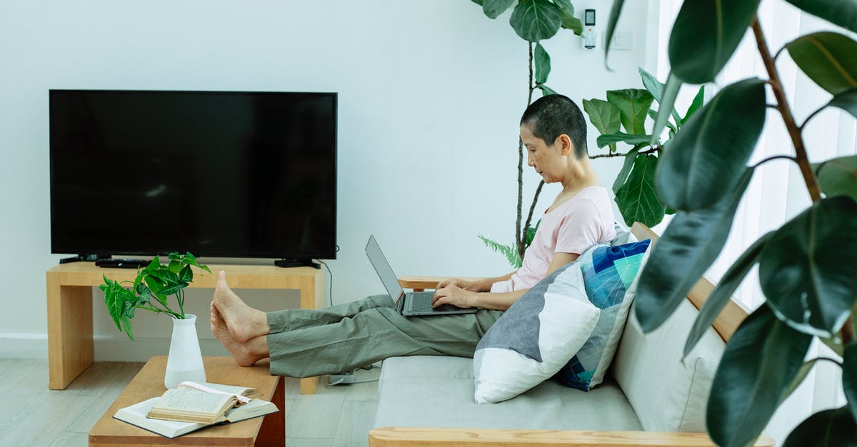 Why does connecting a laptop to a TV via HDMI cause a framerate drop? - Concentrated ethnic woman surfing on laptop on sofa near TV