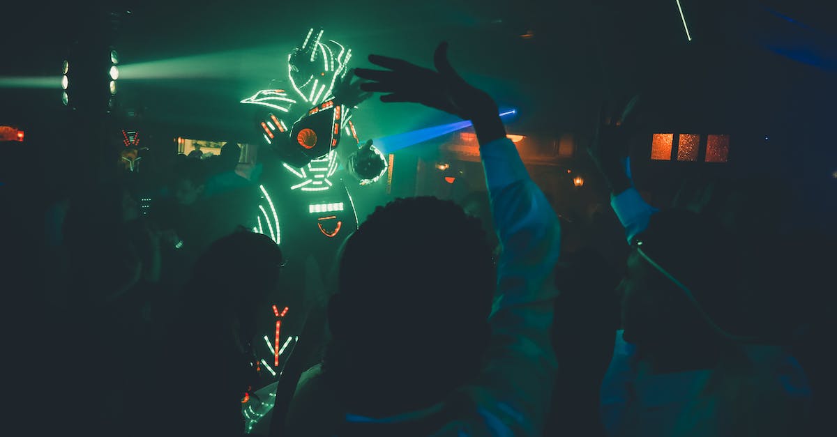 Why does everyone sound like a robot in ps4 party chat - Unrecognizable person in futuristic costume with neon lights making show in dark nightclub near dancing people