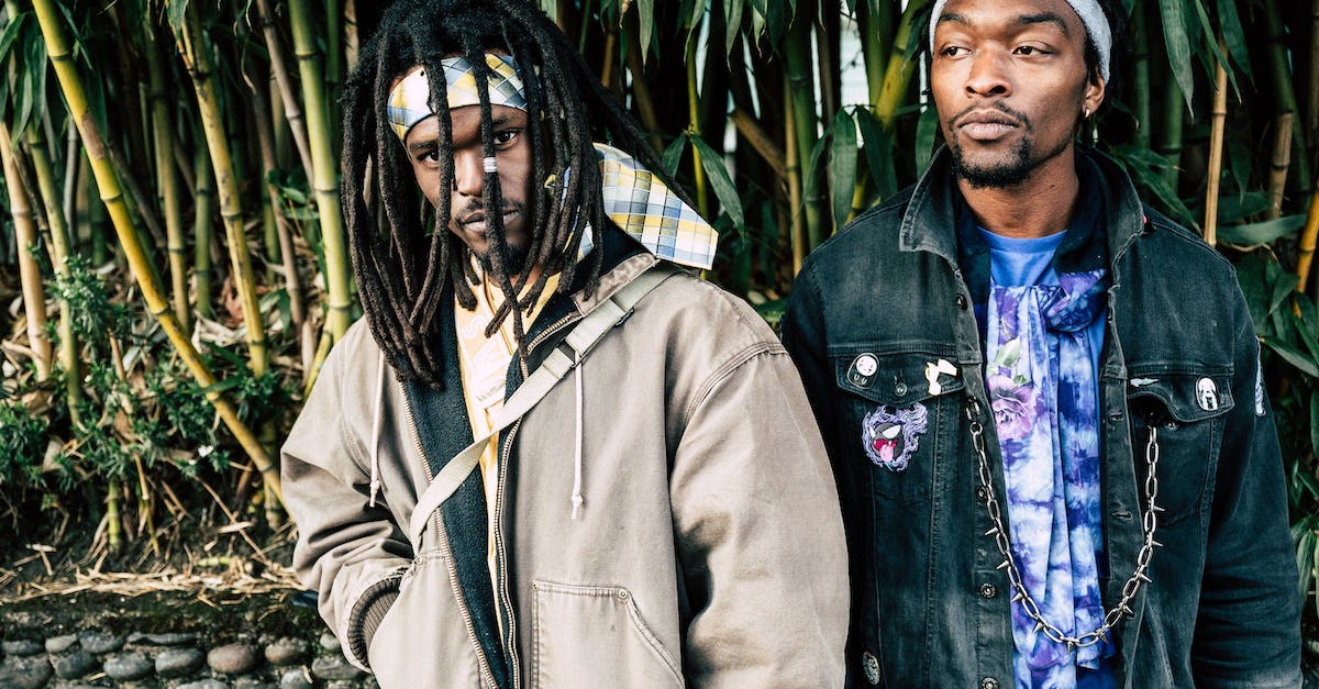 Why does my character not look whilst walking? - Calm confident African American males with dreadlocks wearing street style clothes and headbands standing against tall green trees in garden