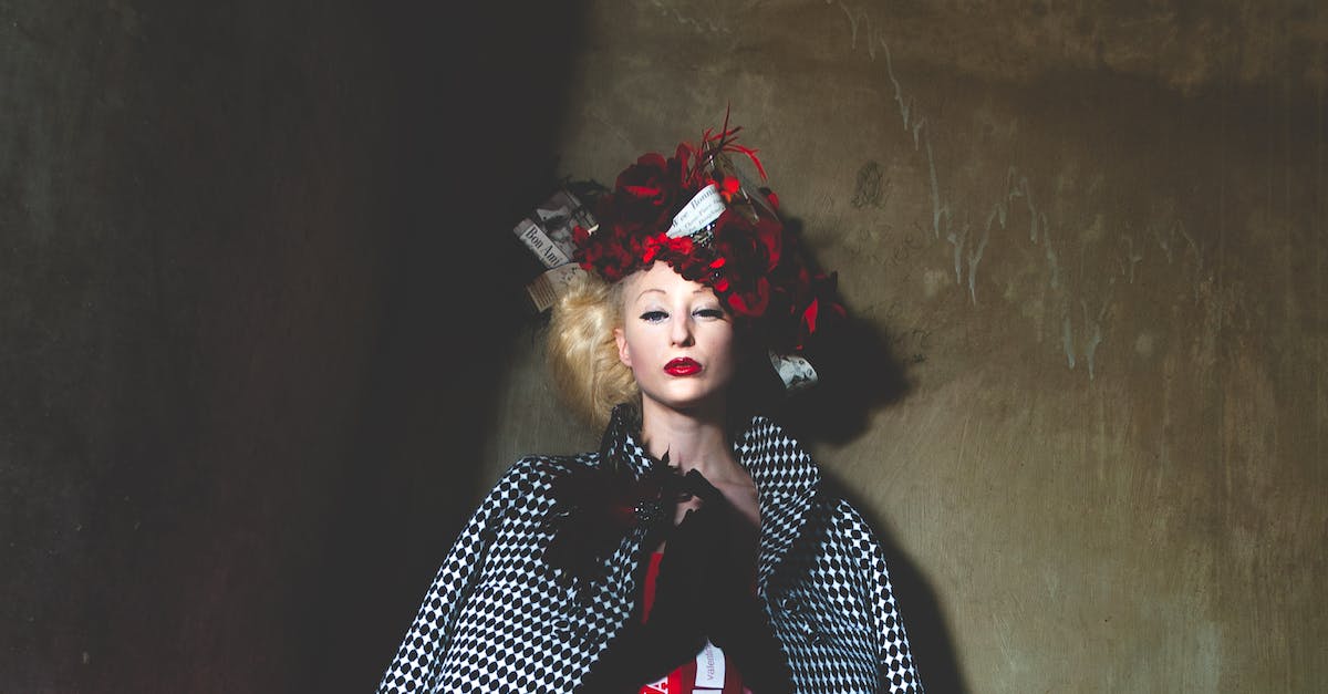 Why does my character not look whilst walking? - Serious young female with bond hair and bright makeup in elegant outfit and creative headdress standing against shabby wall and looking at camera