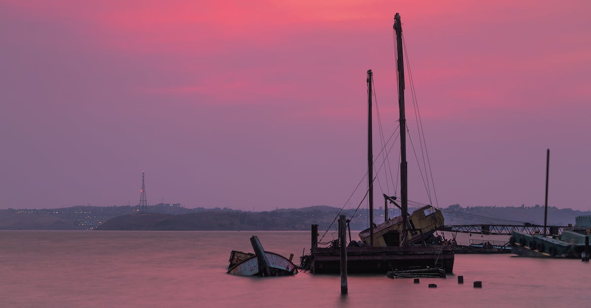 Why does my obsidian boat sink? - Picturesque abandoned vessels floating near aged pier and hills on purple cloudy sunset Why does my obsidian boat sink? - Picturesque abandoned vessels floating near aged pier and hills on purple cloudy sunset