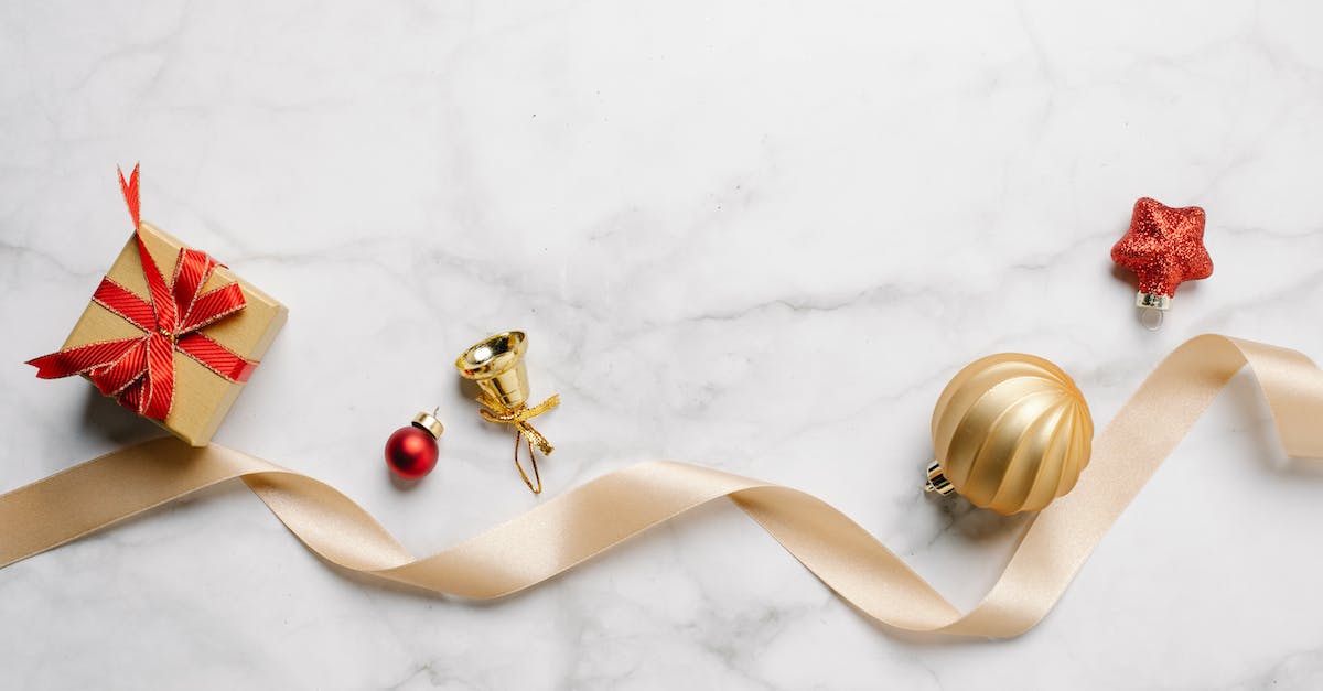 Why does shift-queuing blink have unpredictable results? - Top view of festive Christmas golden bell with bauble and red star near gift box with shiny ribbon on marble