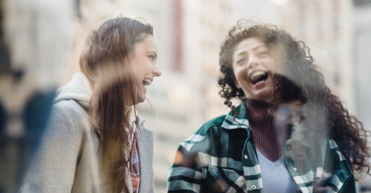 Why have Town Hall outside of farming base? - Through window of smiling multiracial female friends in outerwear having fun while standing near showcase on street on blurred background Why have Town Hall outside of farming base? - Through window of smiling multiracial female friends in outerwear having fun while standing near showcase on street on blurred background