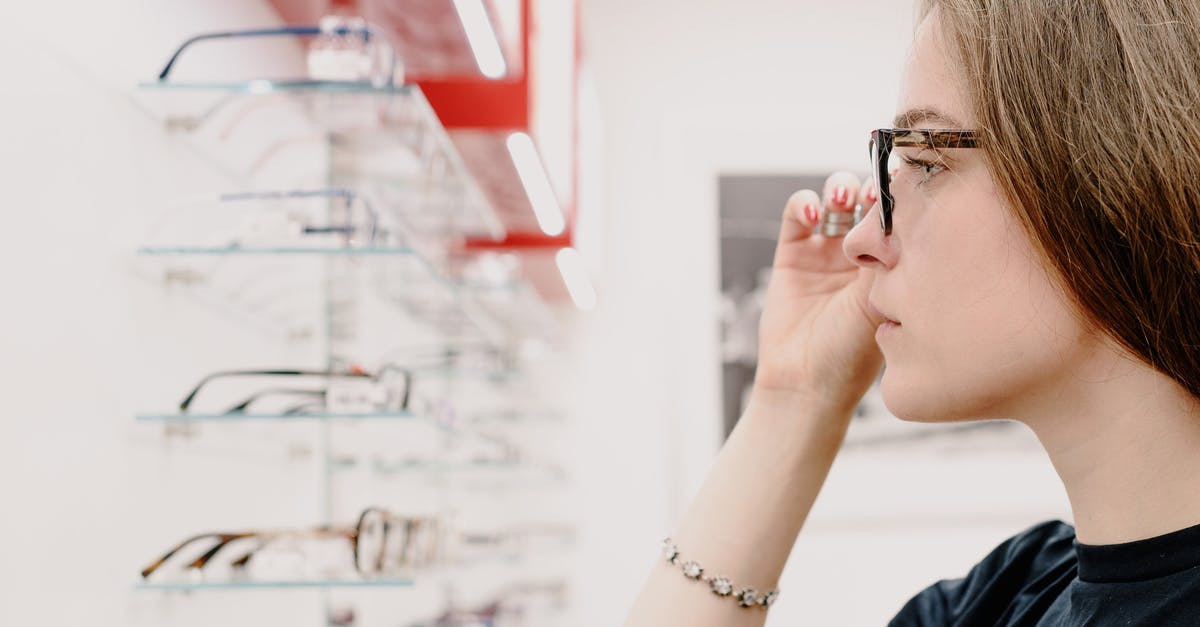 Why is Curie trying to sell me chems? - Side view of crop concentrated female customer putting on eyeglasses for improving eyesight while choosing rim in shop