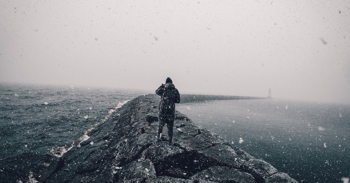 Why is it raining only over generated bodies of water? - Back View of a Person Standing on Breakwater