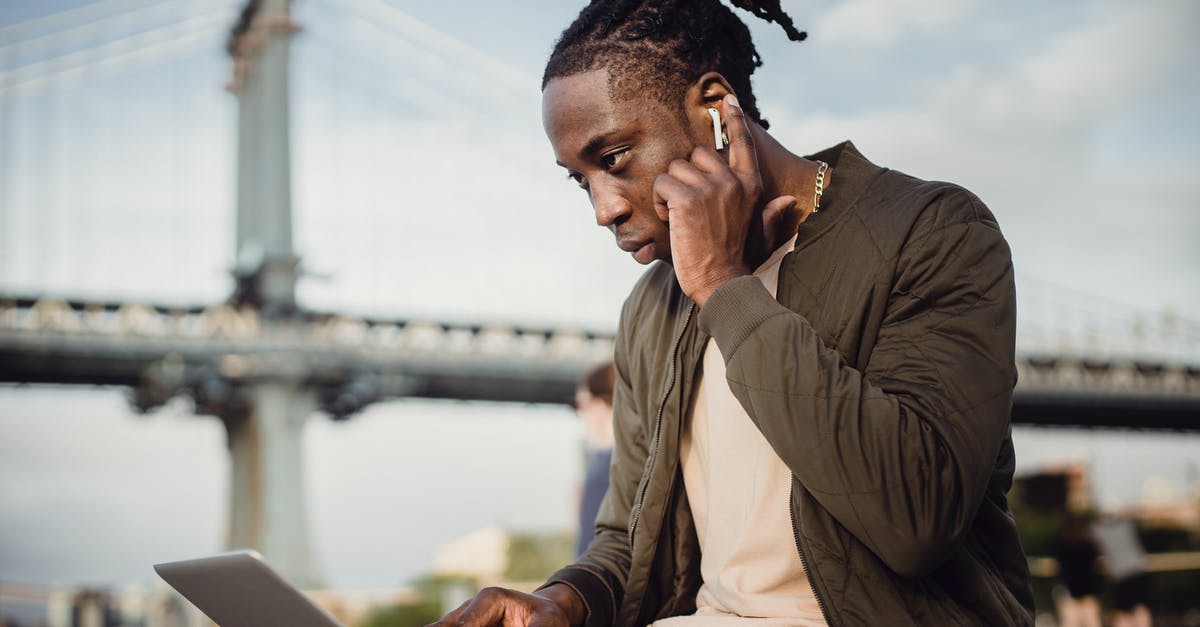 Why is my Call Of Duty Black Ops 2 not loading? - Low angle of concentrated black man in casual wear using laptop and earphones while working outdoors in park