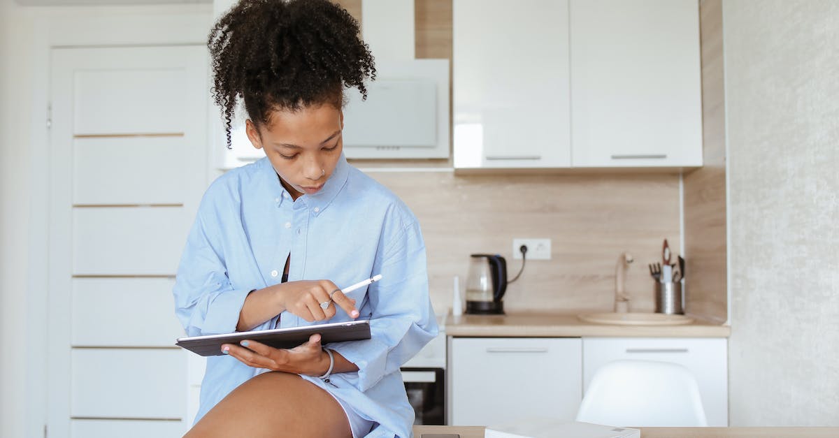 Why is my Wii U tablet home button flashing blue? - A Woman Sitting on the Kitchen Counter Using a Tablet