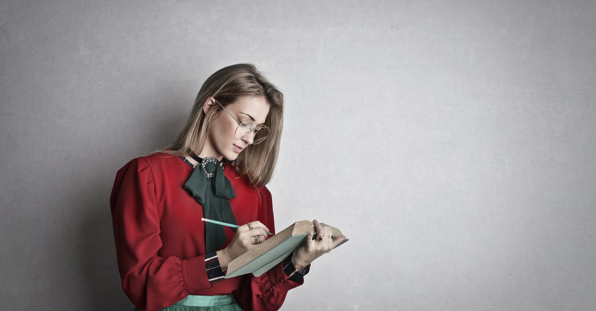 Why is reading/writing memory cards slow in PS1 emulators? - Pensive attentive woman in glasses and elegant vintage outfit focusing and taking notes with pencil in book while standing against gray wall