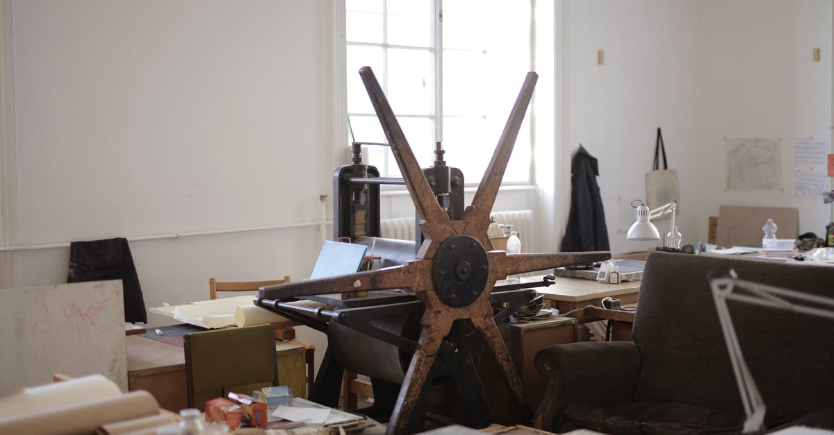 Why isn't my paper mill being provided with lumber? - Workroom with paper rolls on table and white wall with notes and paper rolling machine with wooden mill shape wheel in afternoon