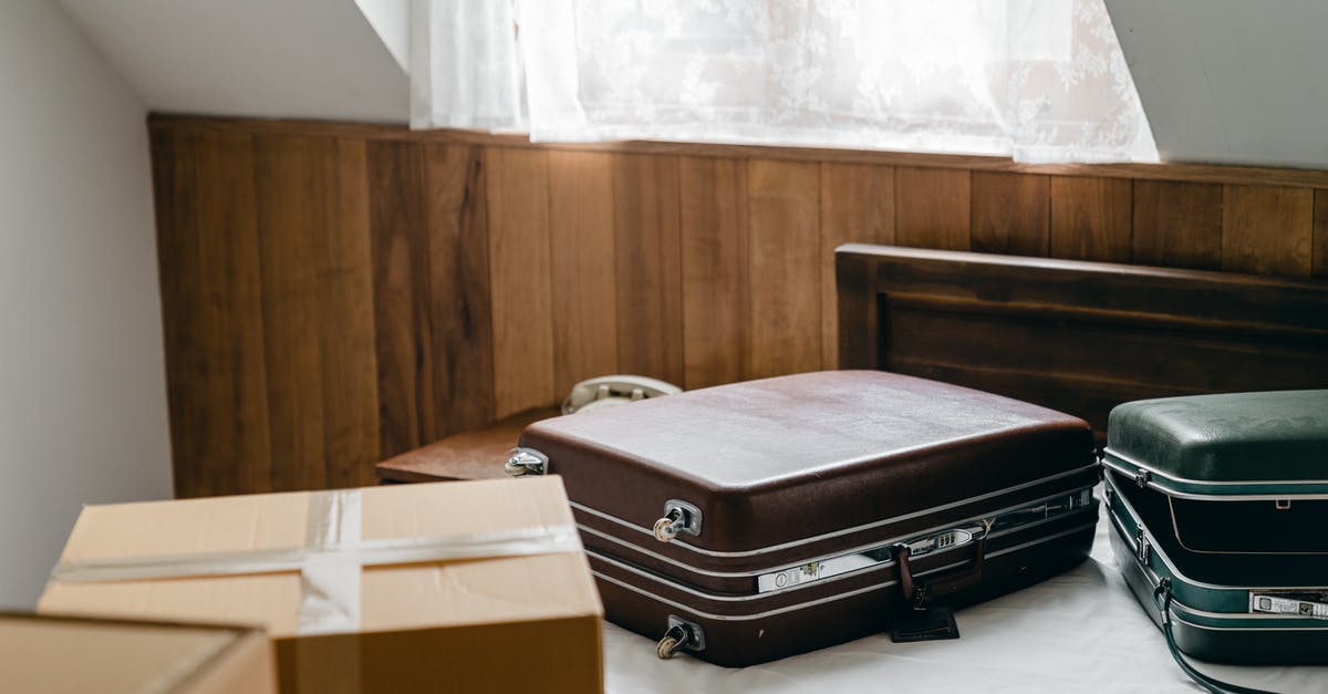Why items such as leather strips keep disappearing from my chests? - From above of brown and green vintage suitcases and packed carton boxes placed on bed with sheet in light room with sloping roof