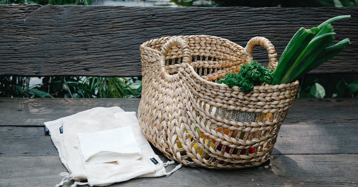 Why reducing agriculture subsidy reduce the unemployment? - Wicker basket with heaped organic vegetables placed on wooden bench near reusable grocery bags in lush garden