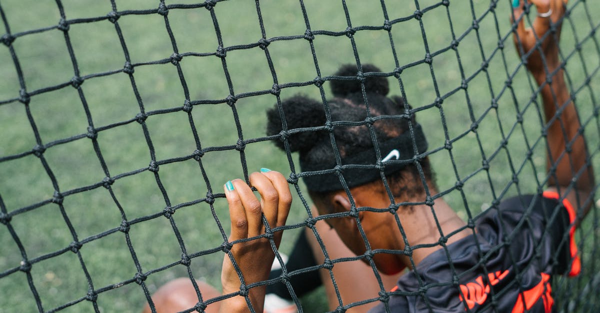Why was Snake in a coma at the start of the game? - Back view of African American teenage football player sitting on field ground and holding grid of gate while preparing to start play football match