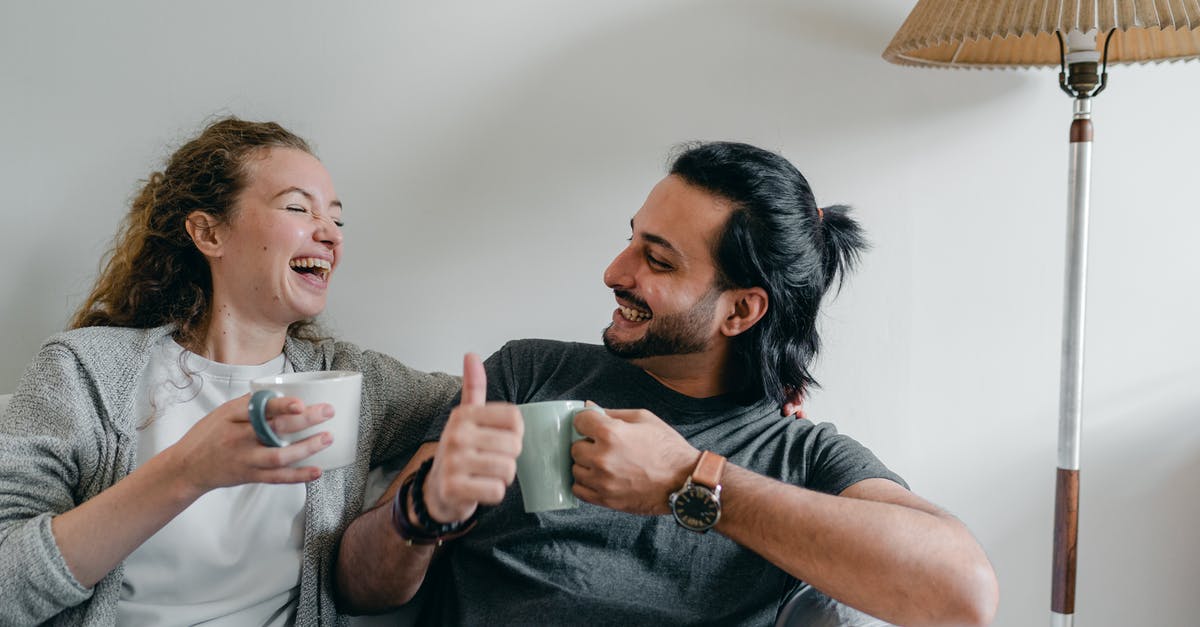 Why won't Vigilante sub-mission end at level 12 like others? - Positive girlfriend in casual wear looking at content ethnic man in smart watch while sitting on cozy sofa with cups of hot beverage and looking at each other