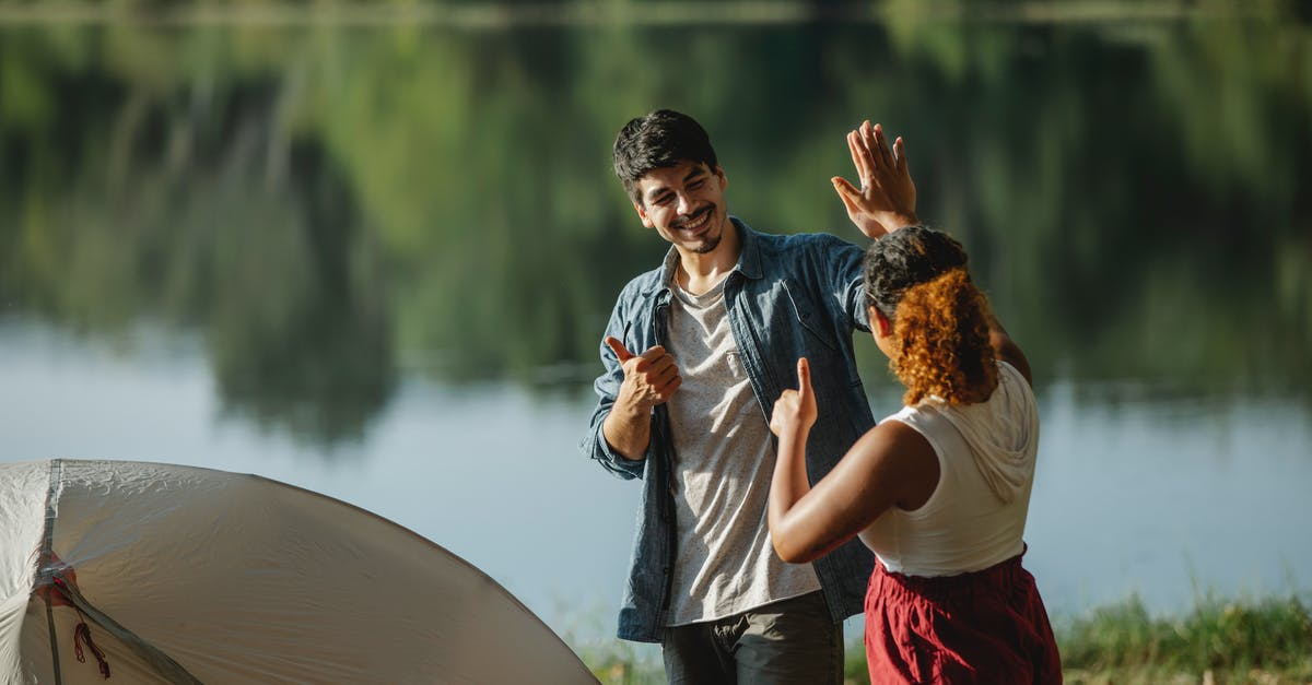Why won't Vigilante sub-mission end at level 12 like others? - Glad male hiker with unrecognizable ethnic female beloved showing thumbs up and giving high five while looking at each other in campsite