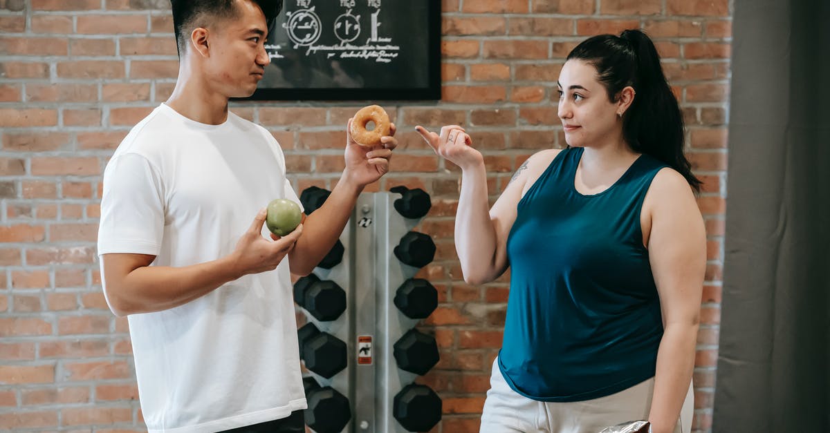 Why would I not choose the Team Offer with the highest bonus? - Side view of Asian personal instructor with apple and doughnut offering healthy food to plus size woman while standing in gym